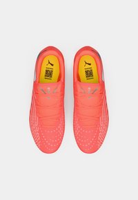 Zapatillas deportivas de color rosa brillante con una parte superior texturizada, que cuentan con una plantilla amarilla y acentos grises, diseñadas para el rendimiento y el soporte.