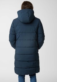 Longue doudoune marine avec capuche, présentant un motif matelassé et des coutures latérales, vue de dos. Le matériau semble lisse et isolant.