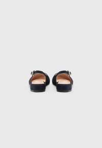 Sandales slingback en daim bleu marine avec un petit talon et une sangle à boucle réglable, dotées d'un doublure intérieure lisse.