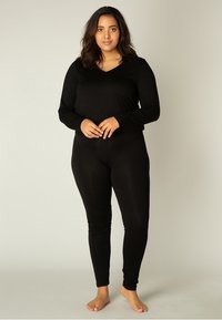 Zwarte jumpsuit met lange mouwen van zachte stof, met een V-hals en een getailleerd ontwerp, voorzien van lange pijpen en een gladde textuur.