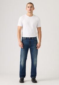 Jeans in denim blu con design a gambe dritte, dettagli sbiaditi e classico stile a cinque tasche. Abbinati a una semplice t-shirt bianca.