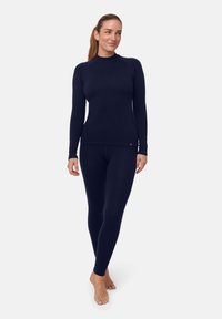 Marineblaues Langarmoberteil und figurbetonte Leggings aus dehnbarem Stoff, mit hohem Kragen und nahtlosem Design sowie kleinem Logo-Akzent.