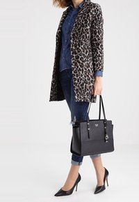 Płaszcz w panterkę, koszula jeansowa, zniszczone dżinsy, czarna torebka i czarne szpilki. Teksturowane materiały, dopasowany krój i elegancki design.
