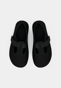 Zwarte waterschoenen van soepel neopreen materiaal, met een open te ontwerp, verstelbare band en uitsparingen aan de zijkanten voor ademend vermogen.