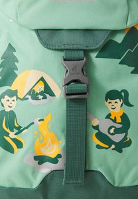 Green fabric backpack featuring a flap with a gray buckle, illustrated with camping scenes: a tent, a campfire, and two figures.