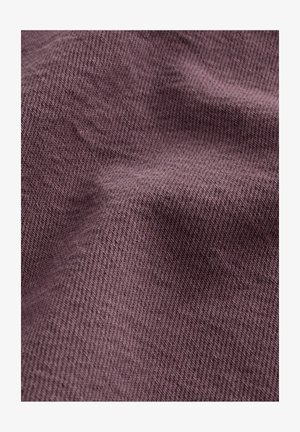 Tissu texturé dans une teinte mauve atténuée, avec un motif de tissage diagonal, montrant de douces plis et ombres pour plus de profondeur.