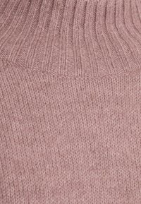 Miękki, różowy dzianinowy materiał z prążkowanym wzorem przechodzącym w gładki splot.