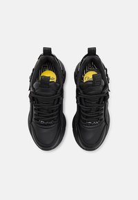 Baskets en cuir noir avec un col rembourré, des lacets texturés et des accents de logo proéminents sur la languette et le côté, offrant une semelle rembourrée.