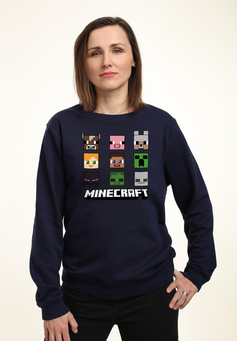 Sudadera azul marino con personajes pixelados de Minecraft en una cuadrícula y la palabra "MINECRAFT" en texto blanco negrita en la parte inferior.