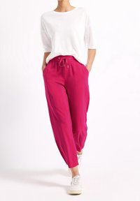 Luftiga fuchsia-byxor med elastisk midja och snörning. I kombination med en vit, kortärmad tröja med rund hals och vita sneakers.