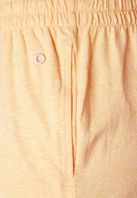 Pantaloni jogger di colore giallo chiaro con vita elastica, dotati di un piccolo accento in metallo e un tessuto testurizzato e morbido.