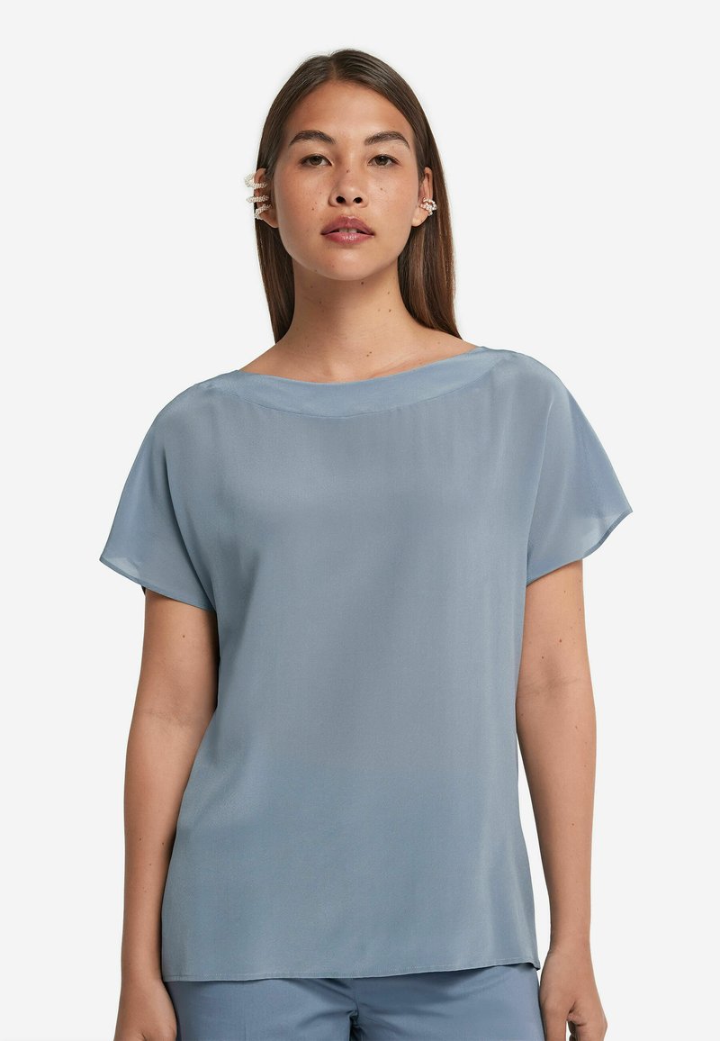 Ljusblå, kortärmad blus med vid halsringning och slät textur. Har lös passform och en flödande design, lämplig för avslappnad användning.