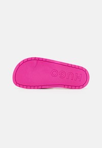 Rubber outsole in bright pink with textured surface and ridged edges. Features 'HUGO' embossed prominently in the center.