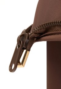 Tirette de fermeture éclair marron sur un tissu à texture lisse. La spirale de la fermeture éclair est visible, et un accent métallique doré est présent à la base.