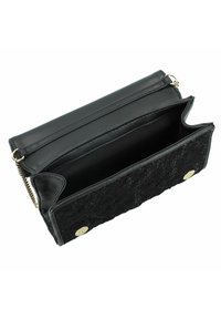 Borsa nera con una parte anteriore in pizzo testurizzato, retro in pelle, chiusura a bottone oro e tracolla a catena. L'interno è spazioso e foderato.