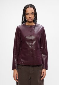 Burgundská kožená bunda s okrúhlym výstrihom, dlhými rukávmi, siedmimi gombíkmi na prednej strane a dvoma prednými vreckami. Hladká, lesklá textúra.