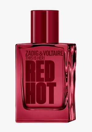 Rød gennemsigtig rektangulær parfume flaske med rød hætte, mærket "Zadig & Voltaire This Is Her! Red Hot" med fed mørkerød tekst.