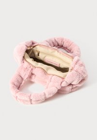Roze faux fur handtas met twee gevlochten handvaten. Het interieur heeft een beige voering en een ritsvak met een label waarop staat "LATEN WE VANDAAG DANSEN."