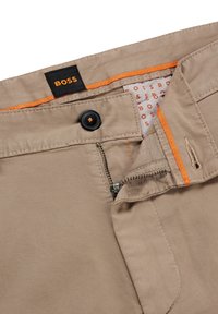 Světle béžové kalhoty se zapínáním na knoflík a zip, s oranžovými švy a vzorovanou podšívkou s logem "BOSS".