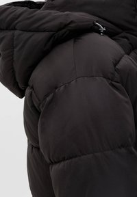 Svart puffjacka med kviltade sektioner, hög krage och insydd nederkant för en tät passform. Mjukt, texturerat tyg med lätt glans.