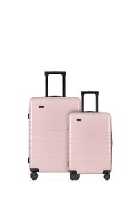 Set of two hard-shell suitcases in pastel pink with black accents, featuring horizontal grooves, extendable handles, and four wheels each.