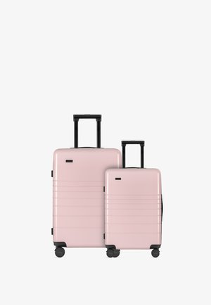 Set di due valigie rigide di colore rosa pastello con dettagli neri, caratterizzate da scanalature orizzontali, maniglie estensibili e quattro ruote ciascuna.