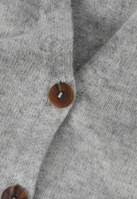 Gray knitted cardigan featuring a smooth texture, V-neck design, and a large brown button accent.