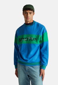 Felpa blu e verde con un audace logo "BENETTON", polsini a coste e dettagli a strisce. Realizzata in tessuto morbido e strutturato.