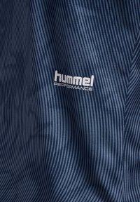 Mörkblått tyg med tunna, oregelbundna vertikala ränder och vit "hummel PERFORMANCE"-logotyp centrerad på materialet.