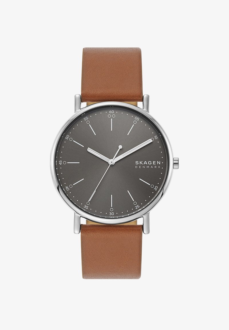 Rund Skagen-klokke med en mørkegrå skive, sølvfargede timeindekser og brun lærrem. Minimalistisk design, rene linjer og polert finish.