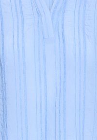 Jasnoniebieska tkanina z pionowymi ciemnoniebieskimi paskami oraz detalem w kształcie dekoltu w serek.