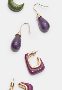 Orecchini a forma di goccia viola con accenti dorati, un crescent verde e un paio geometrico rosa. Presenti varie texture e finiture.