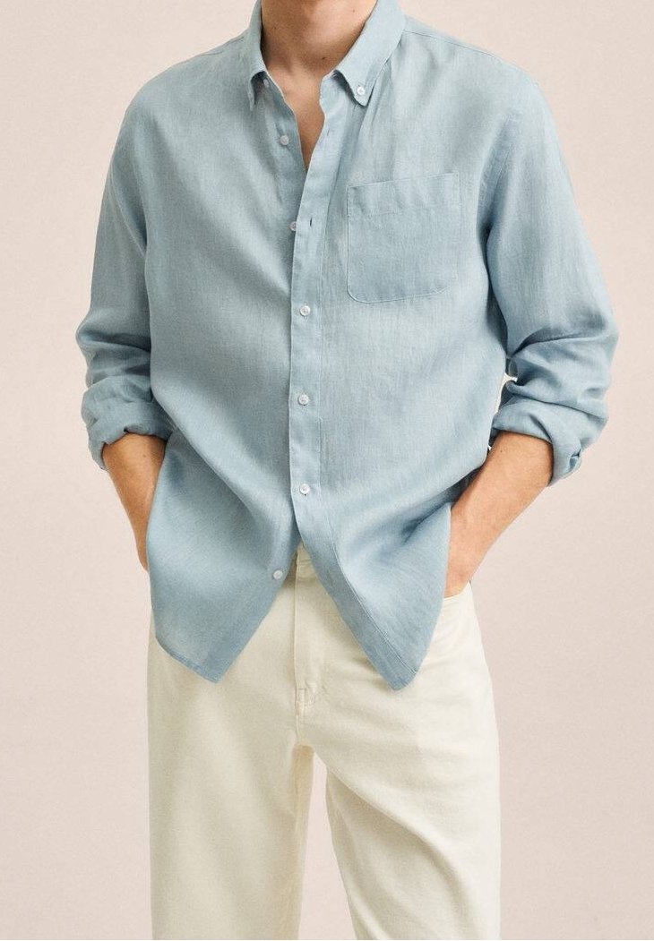 Jasnoniebieska koszula zapinana na guziki, wykonana z teksturowanej tkaniny, z kieszenią na piersi, podwiniętymi rękawami i luźnym krojem, zestawiona z kremowymi spodniami.