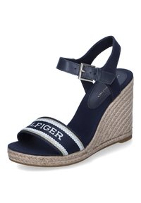Sandalias cuña de color navy con una correa de cuero en el tobillo, parte superior de tela con una banda a rayas y una suela trenzada al estilo espadrille.