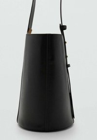 Bolso de cuero negro con un diseño cónico, correa ajustable y acentos de hardware en tono dorado. Textura suave con un detalle de costura mínimo.