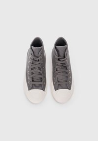 Gray canvas high-top sneakers with white rubber toe cap, metallic eyelets, and flat laces. Features a textured upper and padded collar.