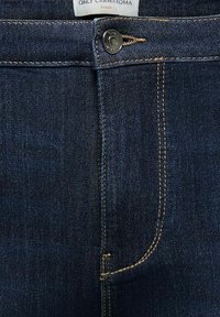 Tummansiniset farkut, joissa on kontrastipistely, etukappaleen napit ja vetoketjukiinnitys sekä etiketti, jossa lukee "ONLY CARMAKOMA".