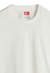 Vit avslappnad kortärmad t-shirt med mjukt tyg, rund halsringning och en etikett med röd och grå text på insidan.