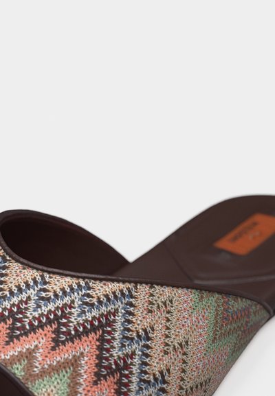 Chaussure sans lacets avec tige en tissu tricoté à motifs zigzag multicolores et semelle ainsi que bordure marron foncé sur fond blanc.
