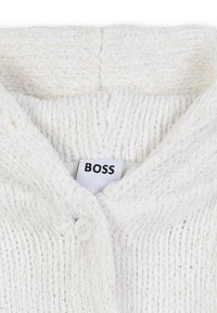 Cardigan en tricot blanc avec un tissu texturé, doté d'un col en V, d'une fermeture à boutons et d'une étiquette marquée "BOSS". Fils métalliques subtils inclus.