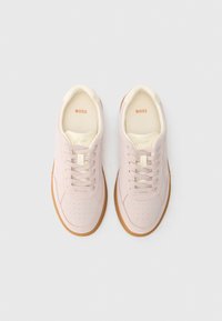 Šviesiai rožiniai sportbačiai su lygiu audinio viršumi, apvalia nosimi ir perforuotu dizainu. Kremo spalvos akcentai ir rudas gumos padas.