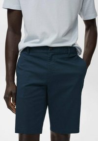 Navy blue shorts made of cotton blend. Classic design with a flat front, side pockets, and a button closure. Smooth texture.