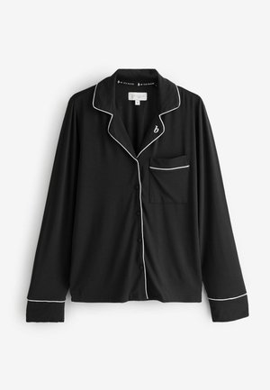 Top pigiama nero a maniche lunghe con piping bianco, chiusura con bottoni e tasca sul lato sinistro. Realizzato in tessuto liscio e morbido.