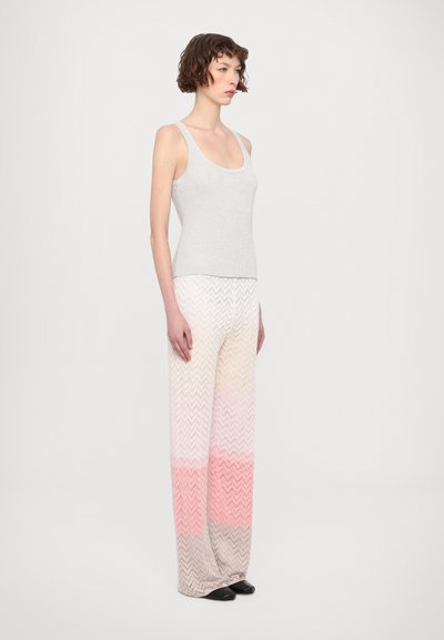 Top gris sin mangas con un diseño ajustado, combinado con pantalones amplios de tonos pastel degradados con un motivo de zigzag y zapatos negros.