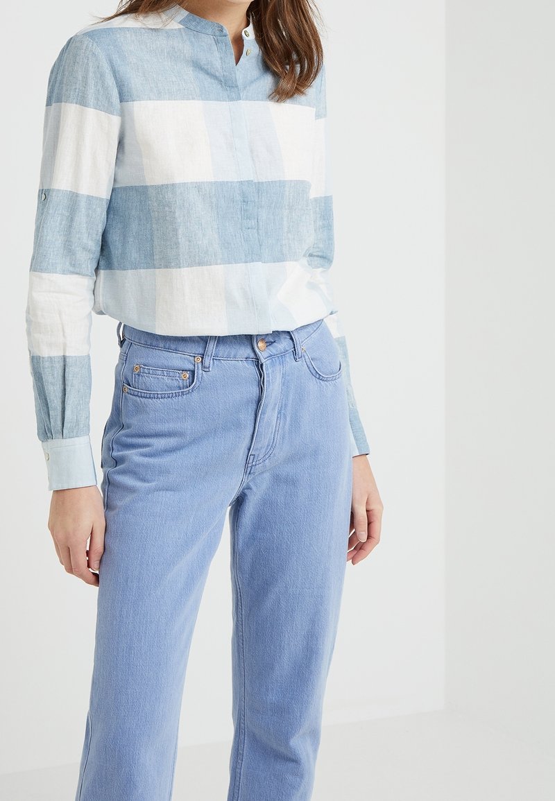 Blå och vit rutig skjorta med knappar, gjord av lättviktig tyg, i kombination med ljusblå högmidjade jeans med framfickor.