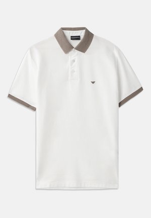Camisa polo blanca con un cuello de punto marrón y acentos en las mangas, que presenta una tapeta de tres botones y un pequeño logo encima del lado izquierdo del pecho.