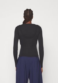 Schwarz, langärmliges Oberteil mit rundem Ausschnitt und gerippter Textur, tailliert und mit einem glatten Stofffinish.