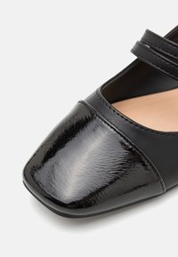 Schwarze Mary Jane Schuhe mit glänzendem Lackzehenkappen, mattem Lederoberteil, doppeltem Riemendesign und quadratischer Zehenform.