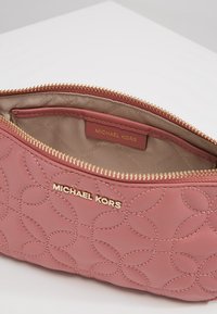 Borsa a pochette in pelle rosa con motivo trapuntato, hardware della cerniera in tonalità oro e logo Michael Kors dorato all'interno. Tessuto liscio.