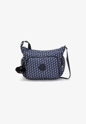 Sac bandoulière à motifs bleu et noir avec poches zippées devant et sur les côtés et un petit porte-clés en peluche noire accroché à la fermeture éclair latérale.